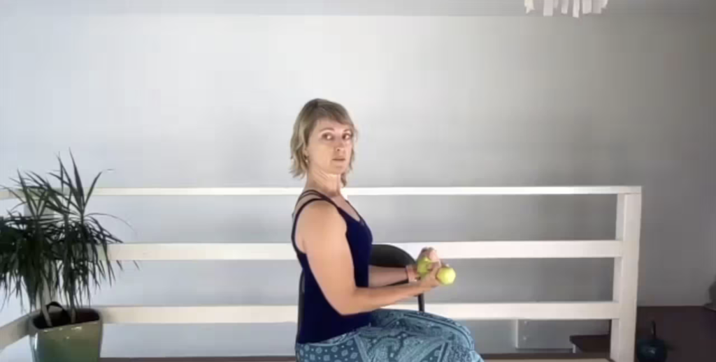 Woman doing Pilates exercises on a chair holding weights.