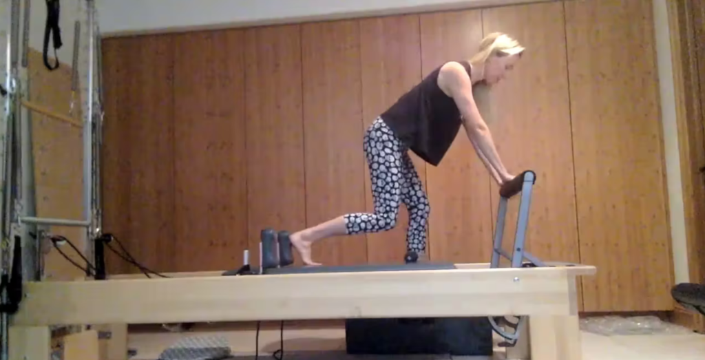 Woman doing Pilates exercises on the Pilates reformer.