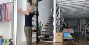 Woman doing Pilates exercises standing using a wall.