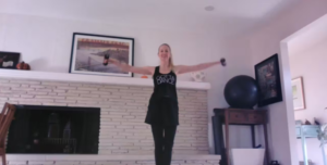 Woman doing standing Pilates arm exercises with weights.