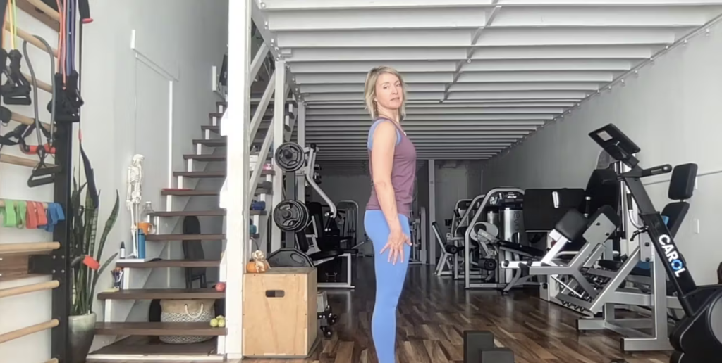 Woman doing standing Pilates exercises.