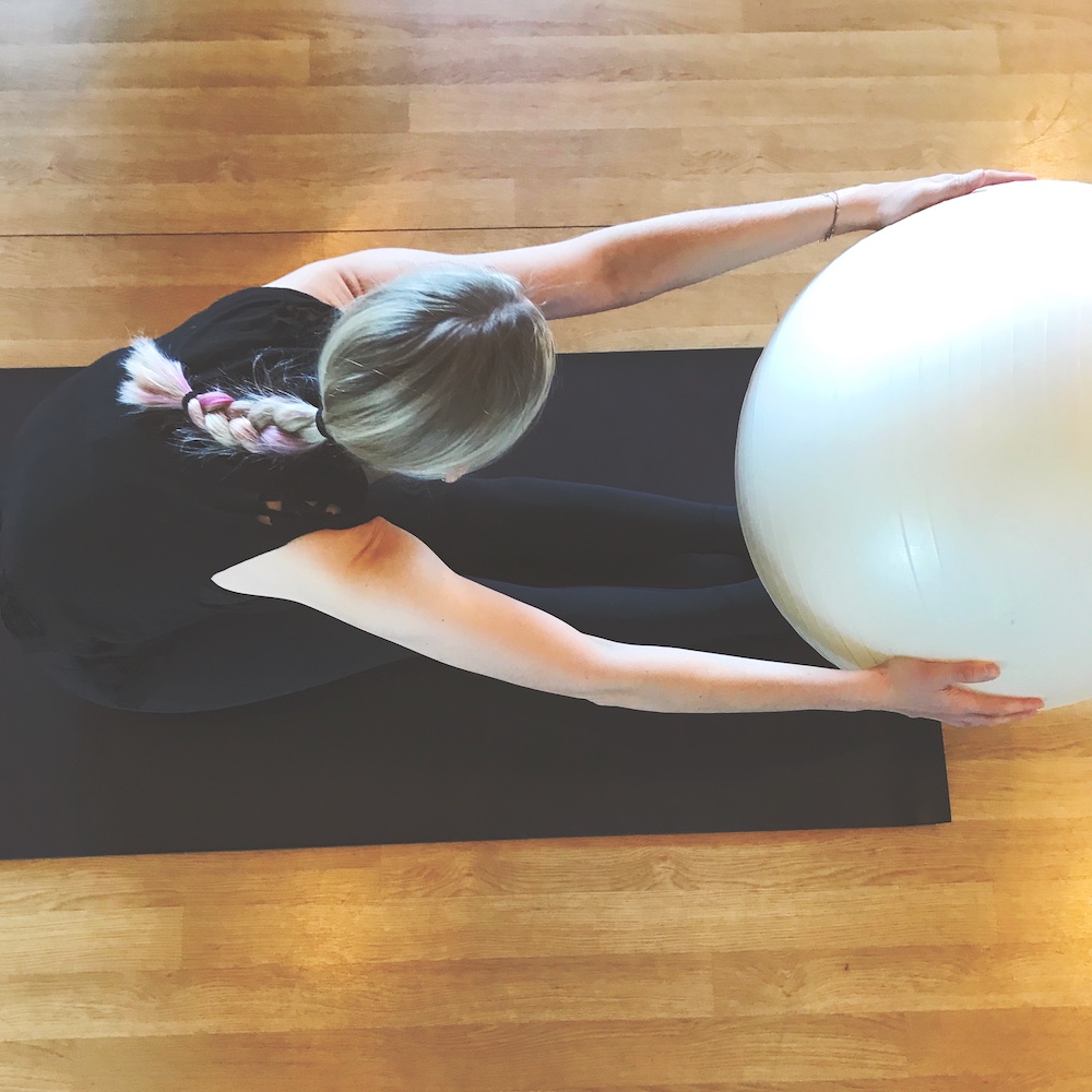 Woman doing a forward bend with Pilates ball