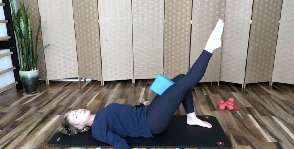 Woman doing Pilates exercises with a yoga block.