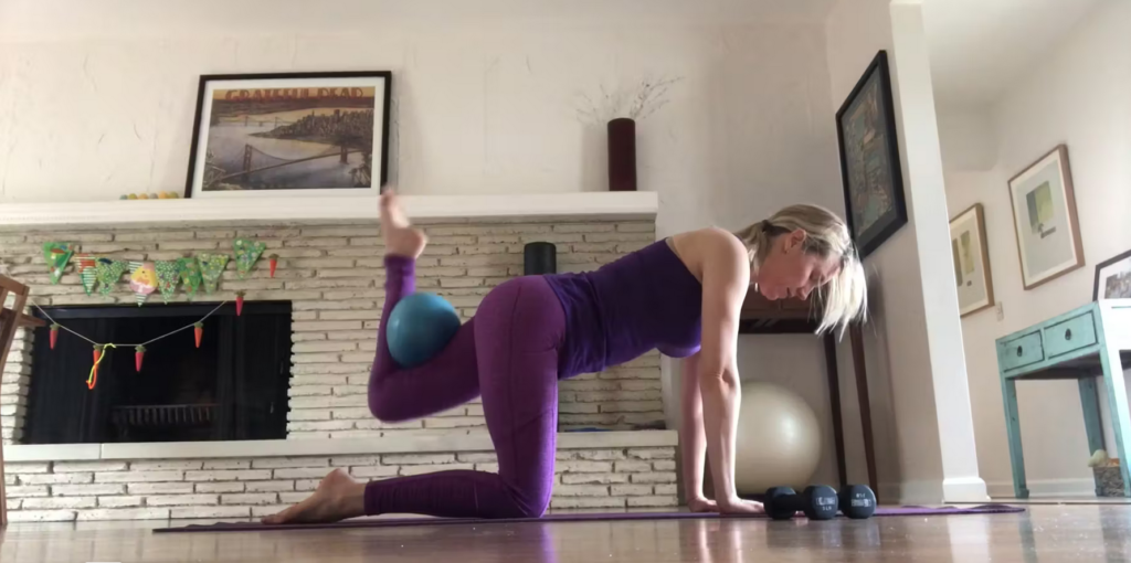 Woman doing Pilates exercises on the Pilates mat with a ball.