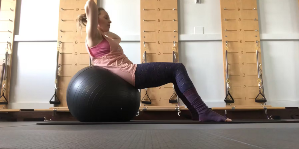 Woman doing Pilates abdominal exercises on the Pilates ball in a Pilates studio.