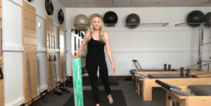 Woman doing Pilates exercises with a foam roller in a Pilates studio.