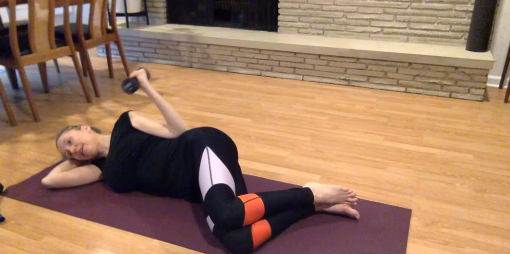 Woman doing Pilates exercises on a yoga mat with a weight.