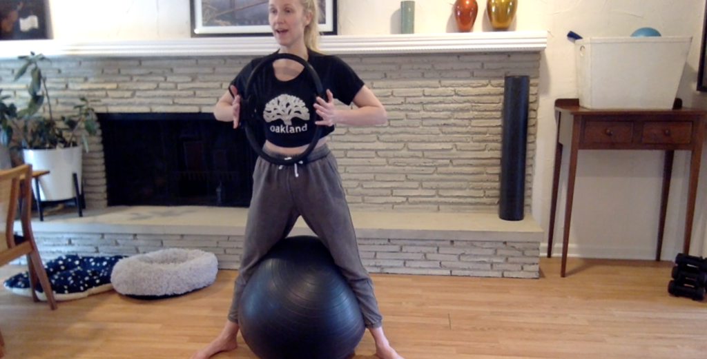 Woman doing standing Pilates exercises with a ball and magic circle.