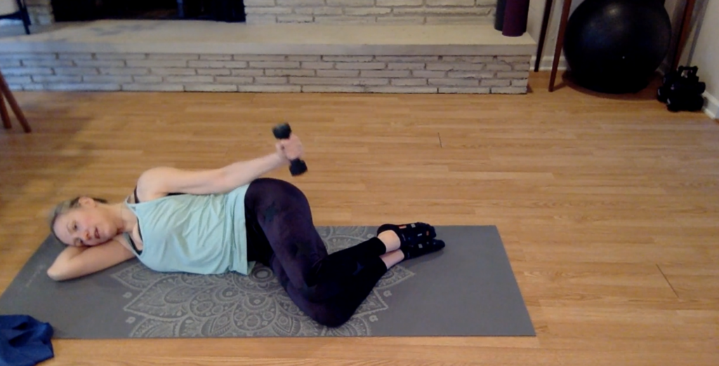 Woman doing Pilates exercises on a yoga mat with weights.