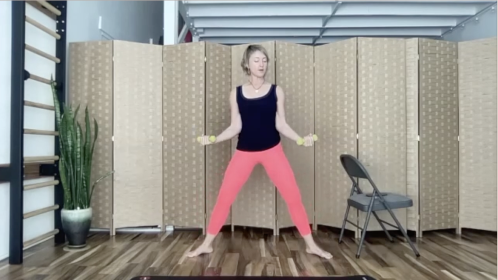 Woman doing standing Pilates exercises with weights.