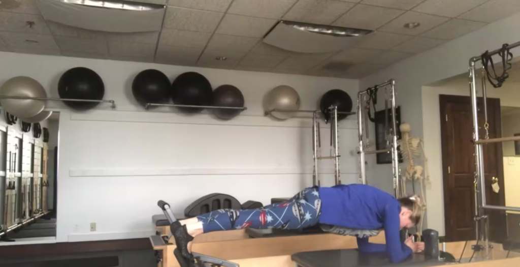 Woman doing Pilates exercises on the Pilates reformer.