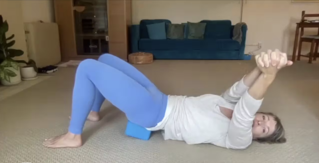 Woman doing Pilates exercises with a yoga block.