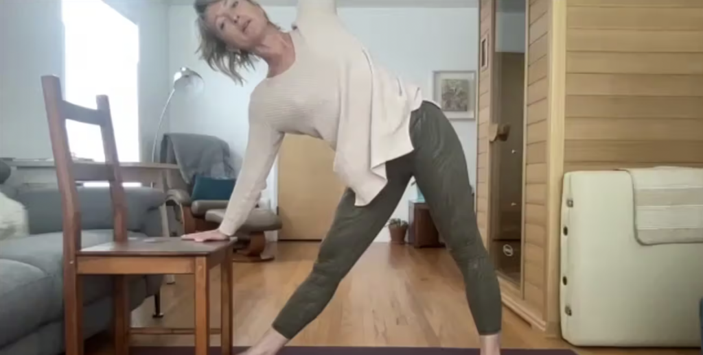 Woman doing Pilates exercises standing with a chair.