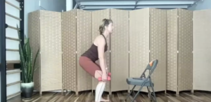 Woman doing standing Pilates exercises with weights.