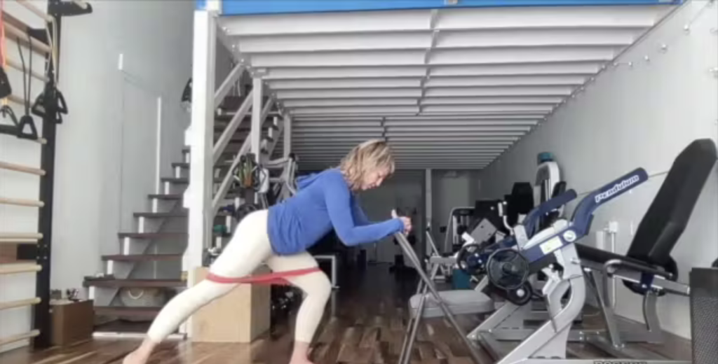 Woman doing standing Pilates exercises on the Pilates mat in a gym.