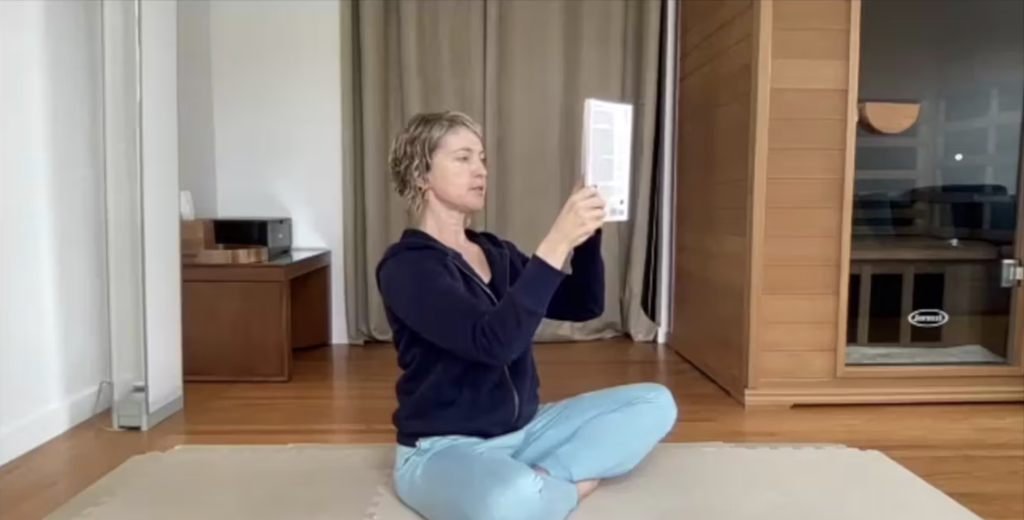 Woman demonstrating correct posture while reading a book on the Pilates mat.