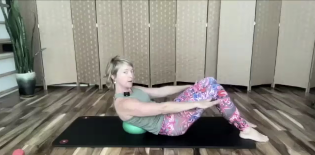 Woman doing Pilates exercises on a yoga mat with a Pilates ball.