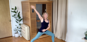 Woman doing PIlates stretches with one arm stretched up.