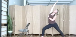 Woman doing Pilates exercises standing. She is lunging with one arm stretched upward.