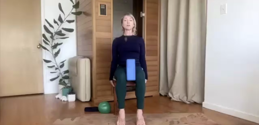 Woman doing Pilates exercises seated in a chair.