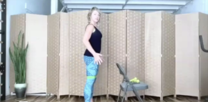 Woman doing standing Pilates exercises in front of a chair.