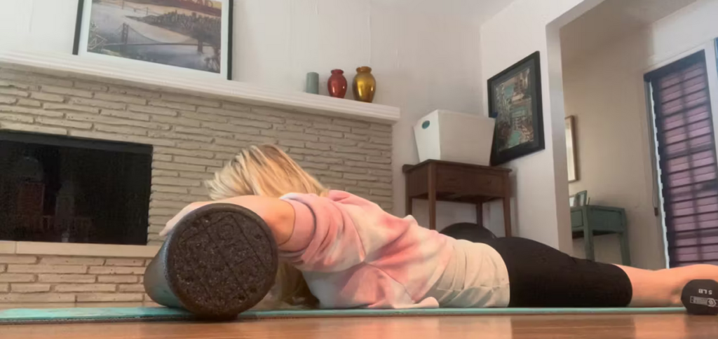 Woman lying on Pilates mat doing exercises with a foam roller