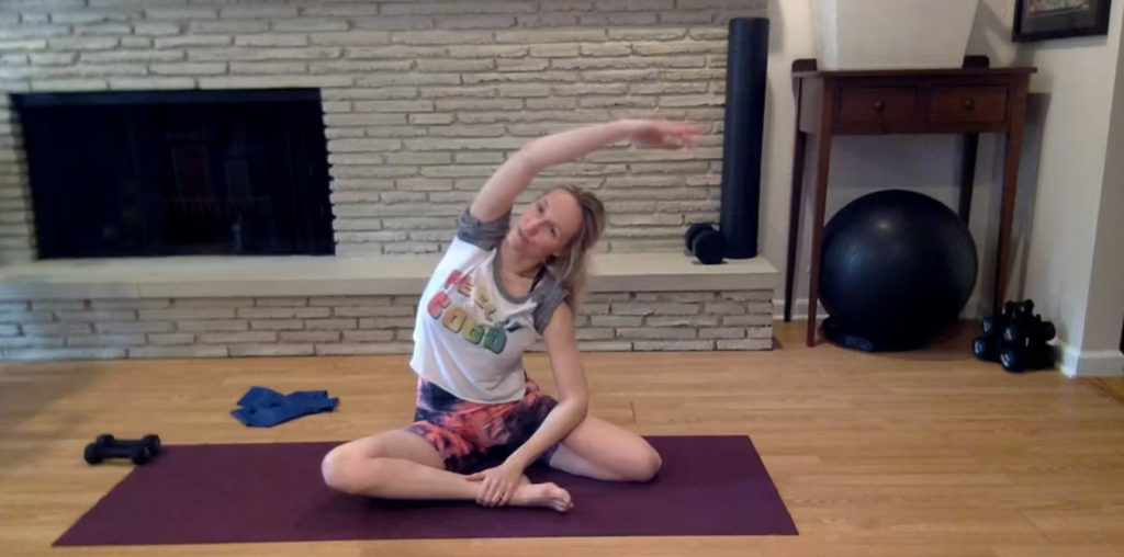 Woman doing Pilates mermaid stretches on her yoga mat.