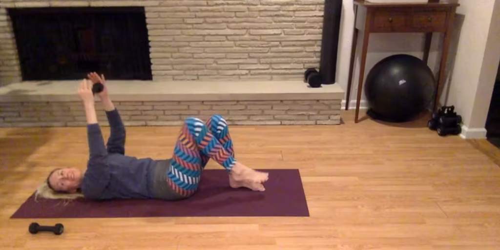 Woman doing Pilates exercises holding a weight.