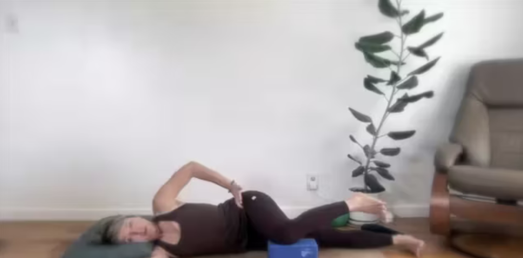 Woman doing Pilates exercises lying on her side on her yoga mat.