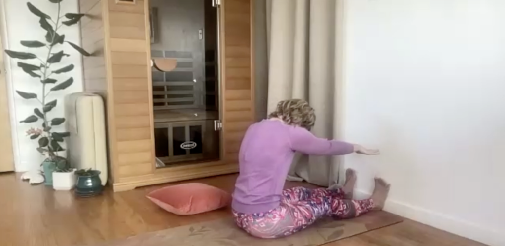 Woman doing Pilates stretches against a wall.