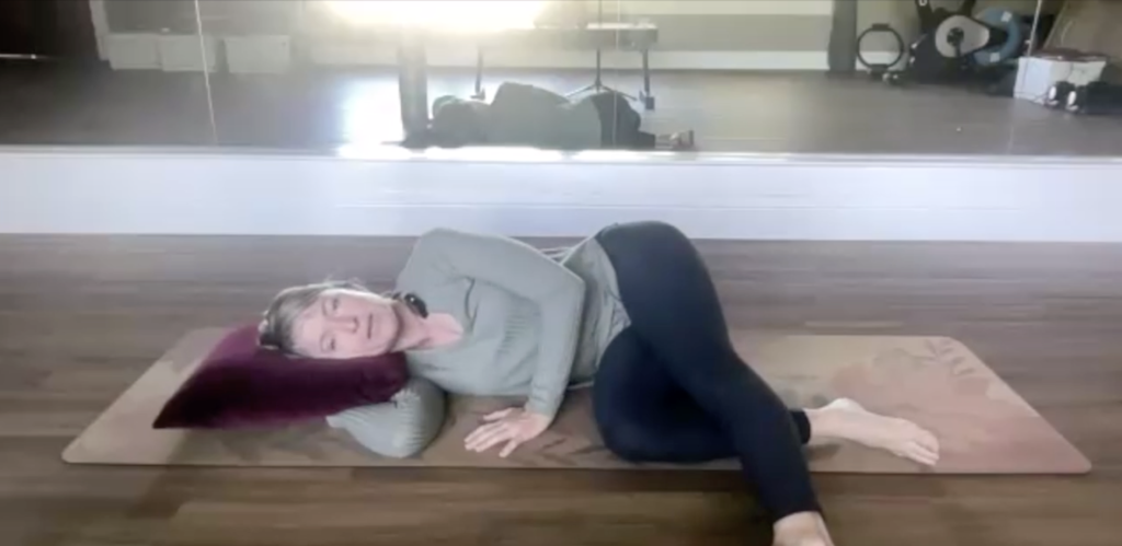 Woman doing Pilates exercises lying on her side on her Pilates mat.