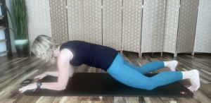 Woman doing a plank exercise on her Pilates mat. She is on her forearms and knees.