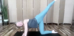 Woman doing Pilates exercises on her Pilates mat. Her leg is extended in the air.