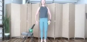 Woman standing doing Pilates and barre exercises. There are weights in her hand.