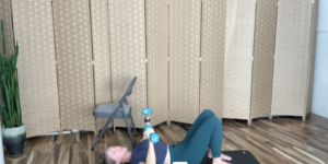 Woman doing Pilates mat exercises on the floor lying on her back with weights in her hands