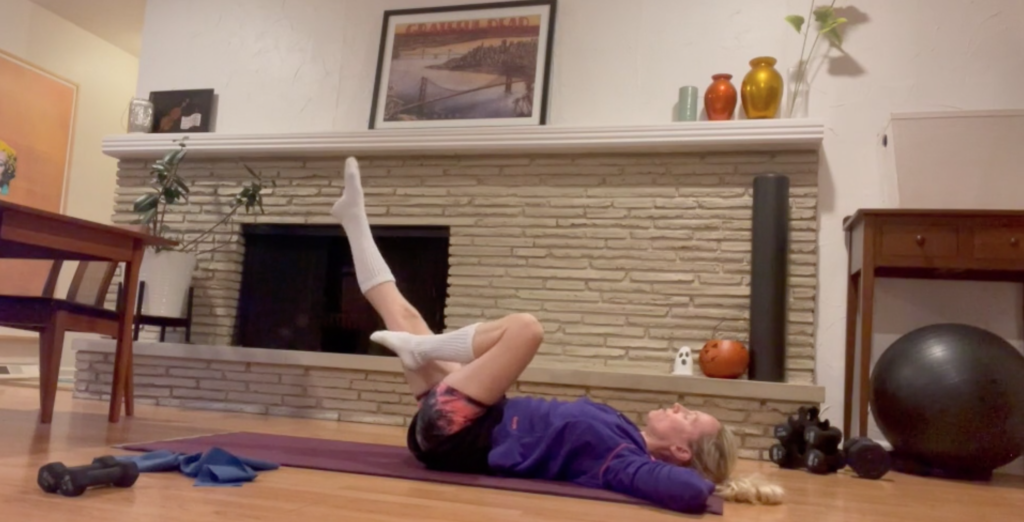 Woman on Pilates mat on the floor doing exercises with one leg extended