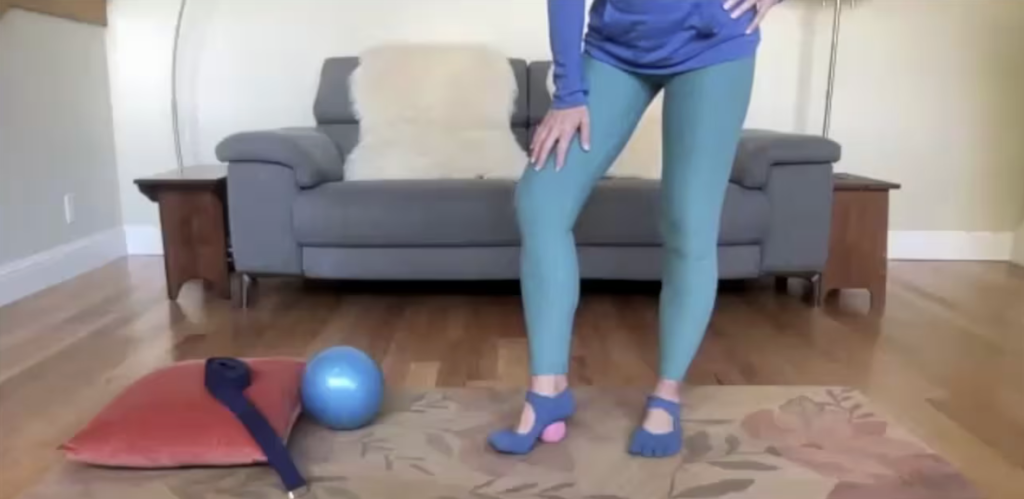 Woman doing Pilates exercises and rolling her foot with a ball.