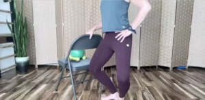 Woman standing holding on to a chair doing Pilates and barre exercises.