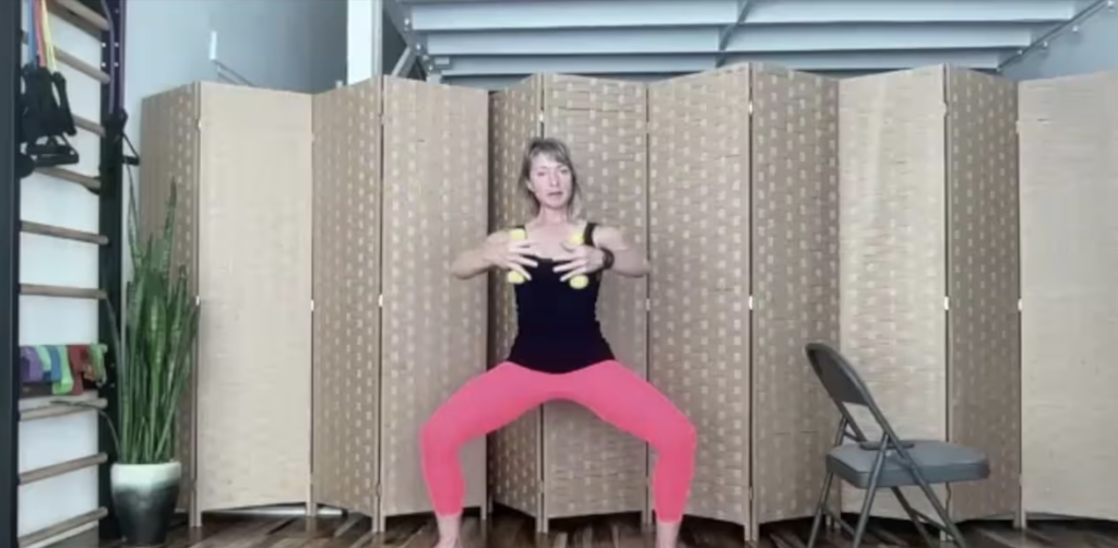 Woman squatting holding weights for barre and Pilates exercises.