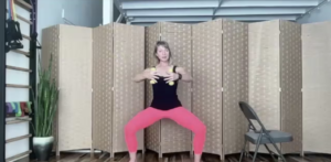 Woman squatting holding weights for barre and Pilates exercises.