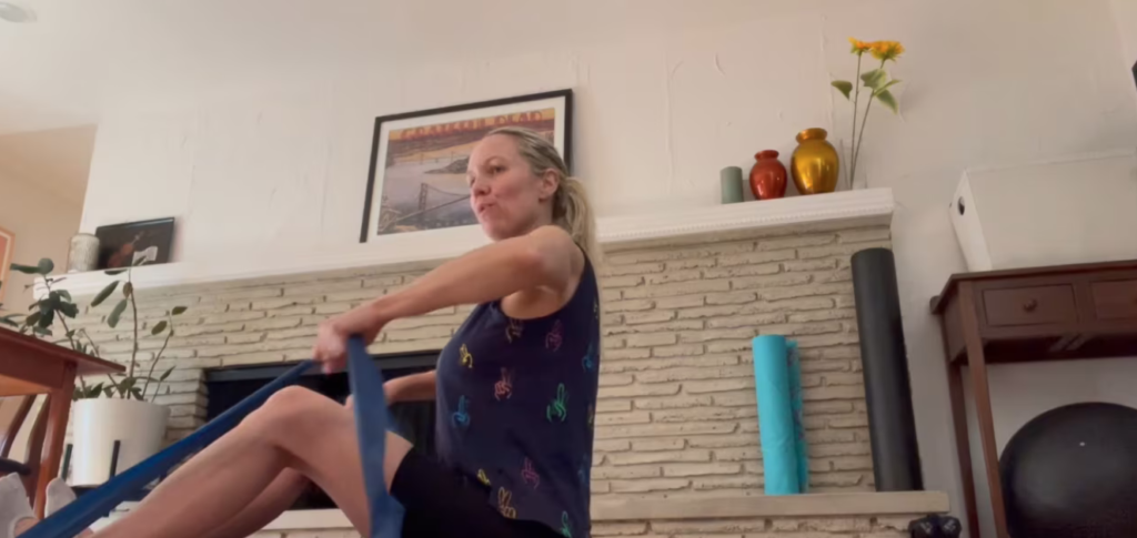 Woman doing Pilates abdominal and arm exercises with theraband on the mat