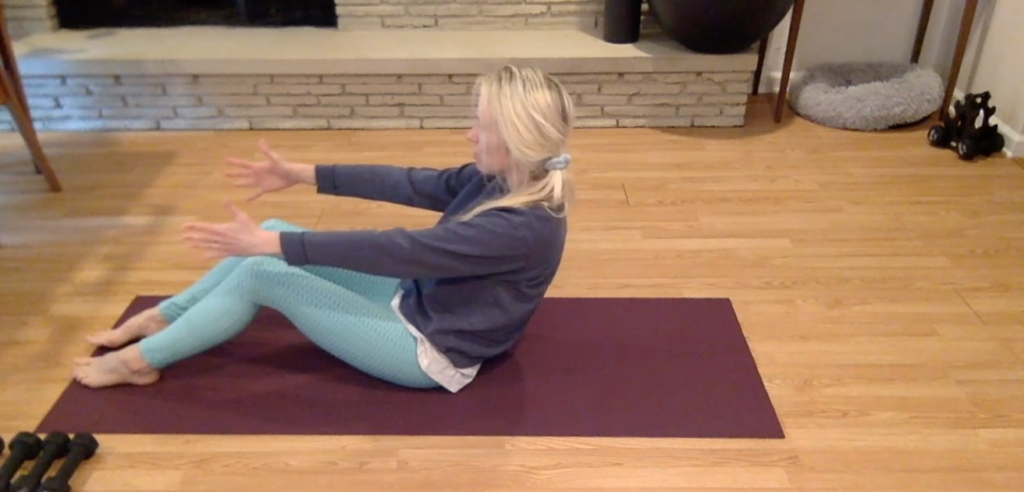 Woman seated on Pilates mat doing Pilates exercises.