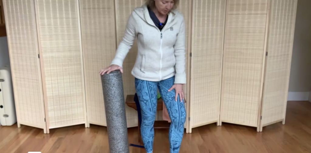 Woman standing doing Pilates exercises with a foam roller