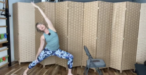 Woman doing a standing lunge with one arm up in a Pilates virtual class.