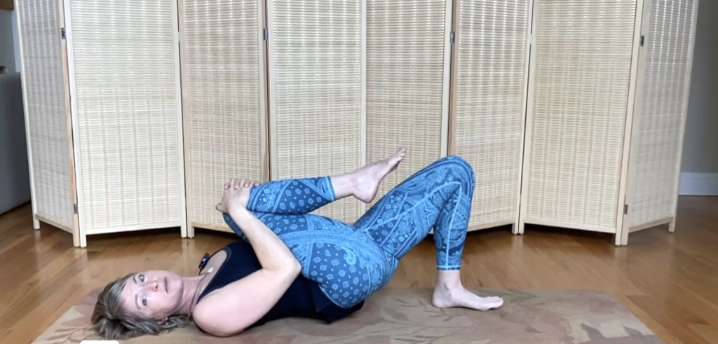 Woman doing Pilates on a Pilates mat with one leg bridging.