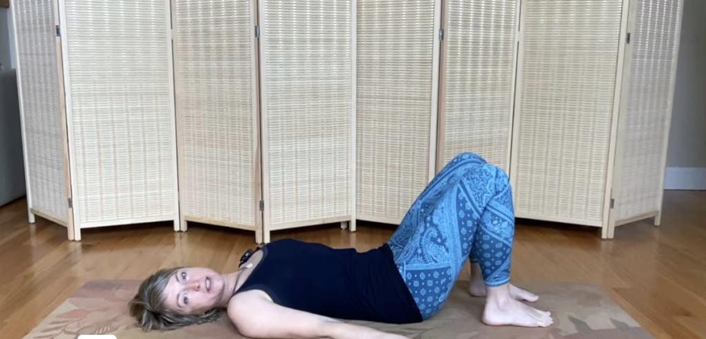 Woman lying on a Pilates mat doing Pilates exercises.