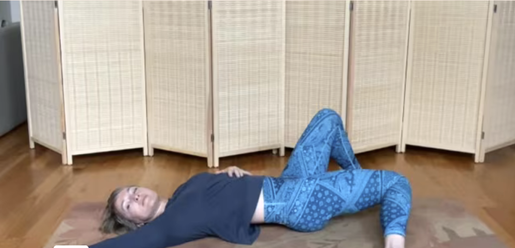 Woman lying on a yoga mat stretching.