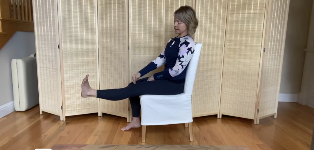 Athletic woman seated in a chair doing Pilates exercises for knee strength.