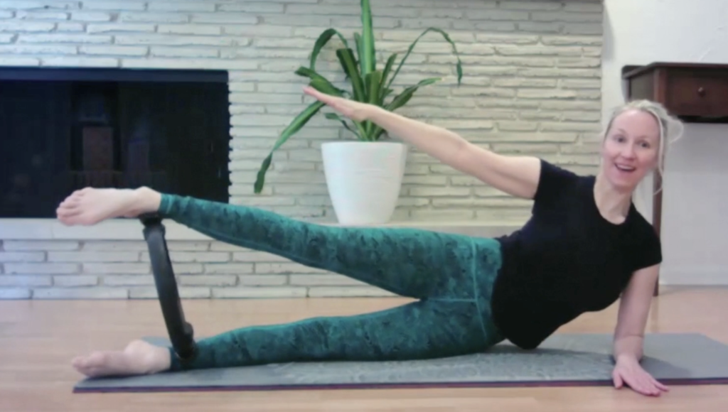 Woman lying on the floor on her side doing Pilates exercises with a magic circle.