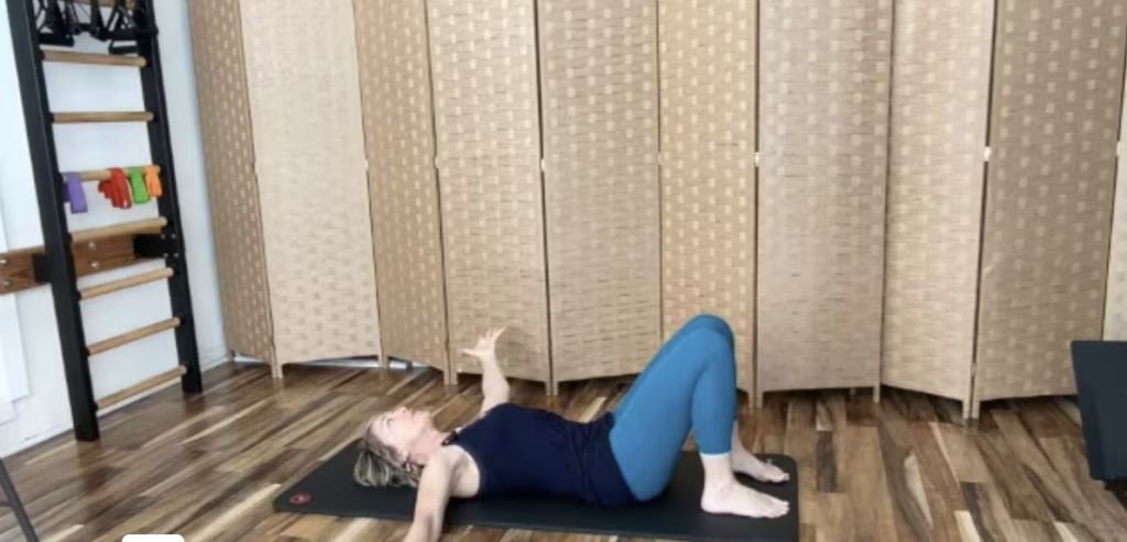 Woman lying on a yoga mat doing Pilates exercises for shoulders.